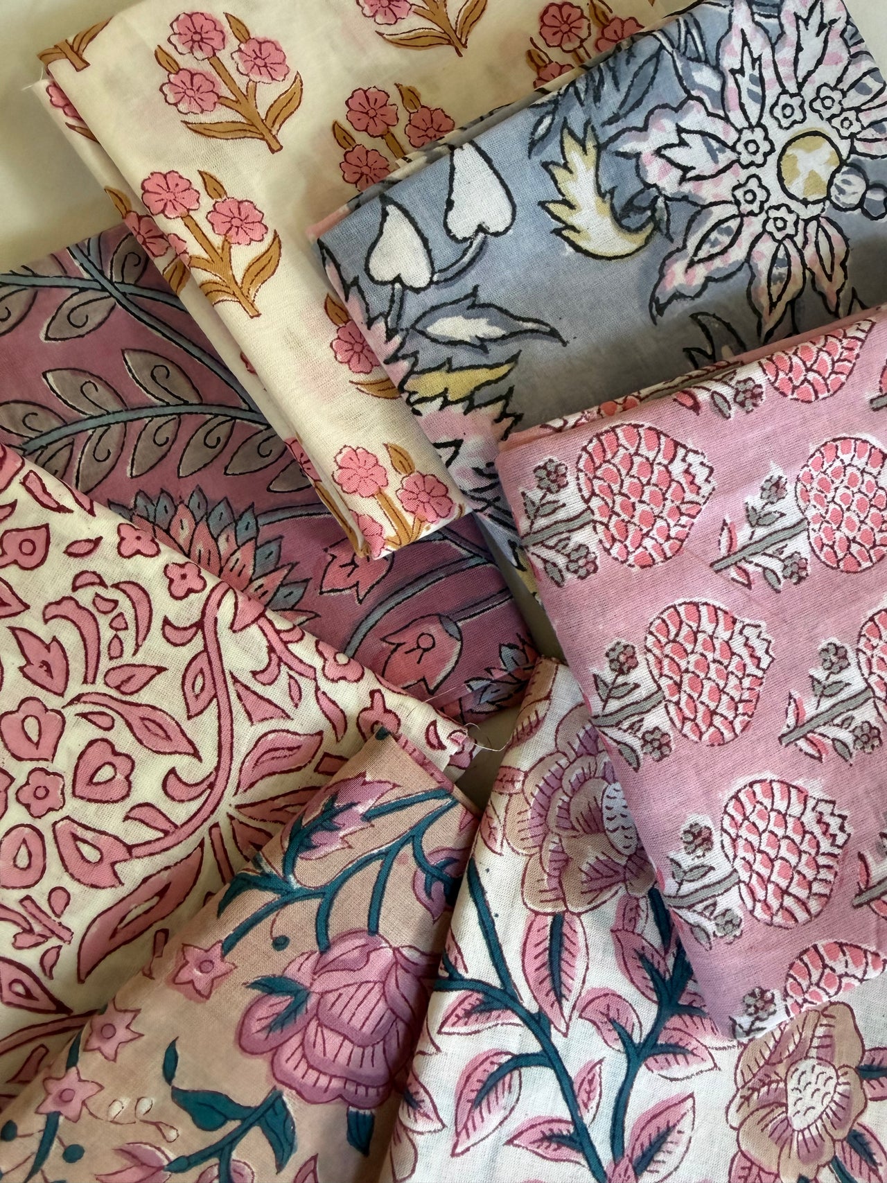 Collection of patterned fabrics with floral and abstract designs.