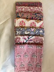 Set of five folded fabric swatches with floral patterns on a light background