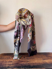 Person wearing a colorful patterned scarf on a wooden surface with a plain background