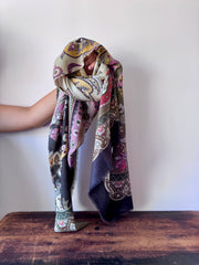 Colorful patterned scarf draped over a wooden surface with a plain background