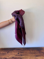 Hand holding a maroon towel over a white background