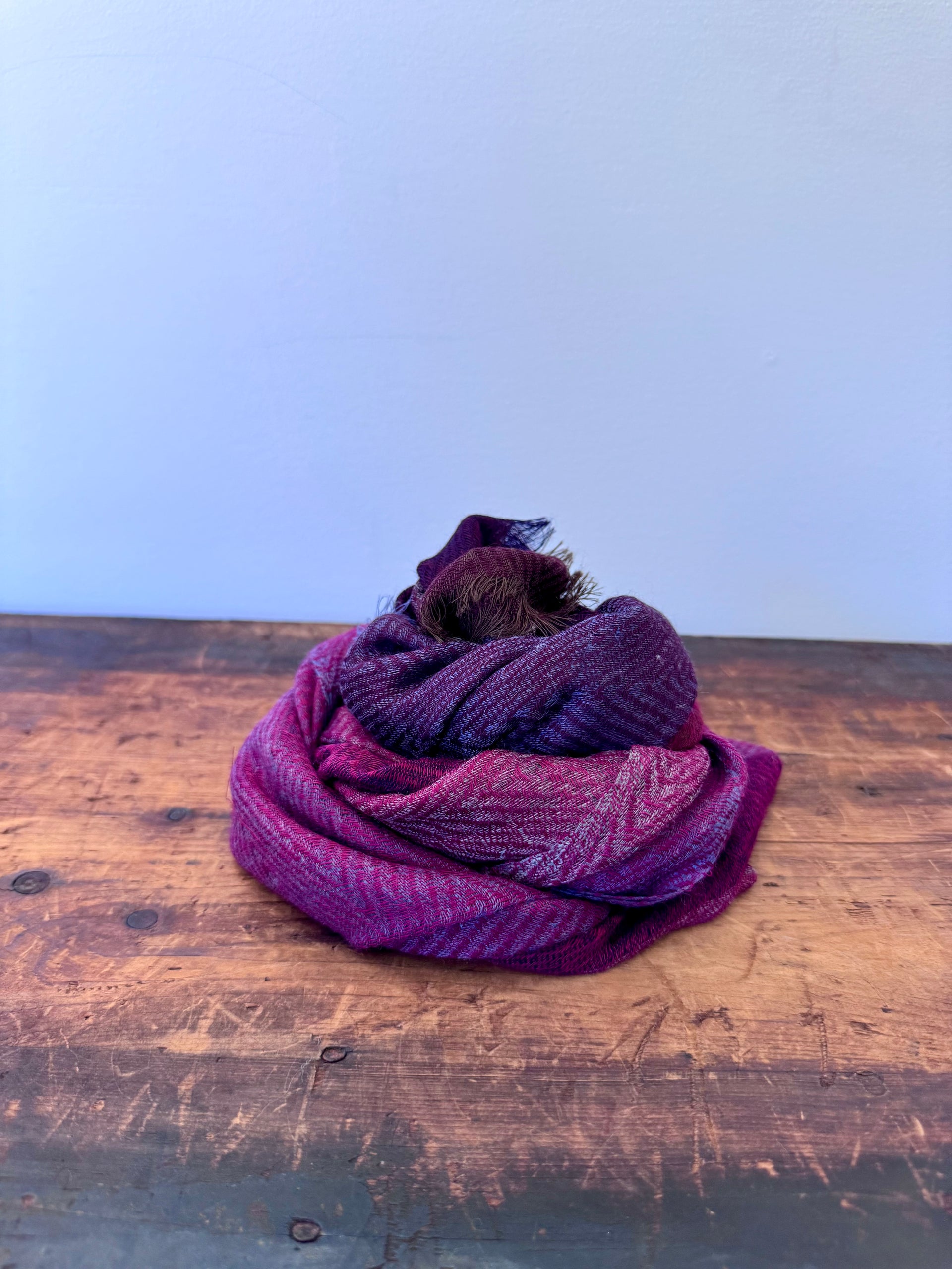 Purple scarf on a wooden surface with a light blue background