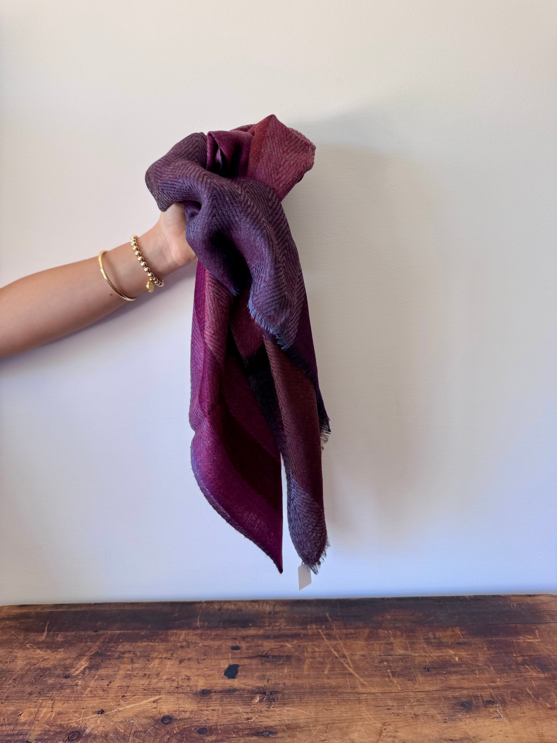 Hand holding a maroon towel over a white background