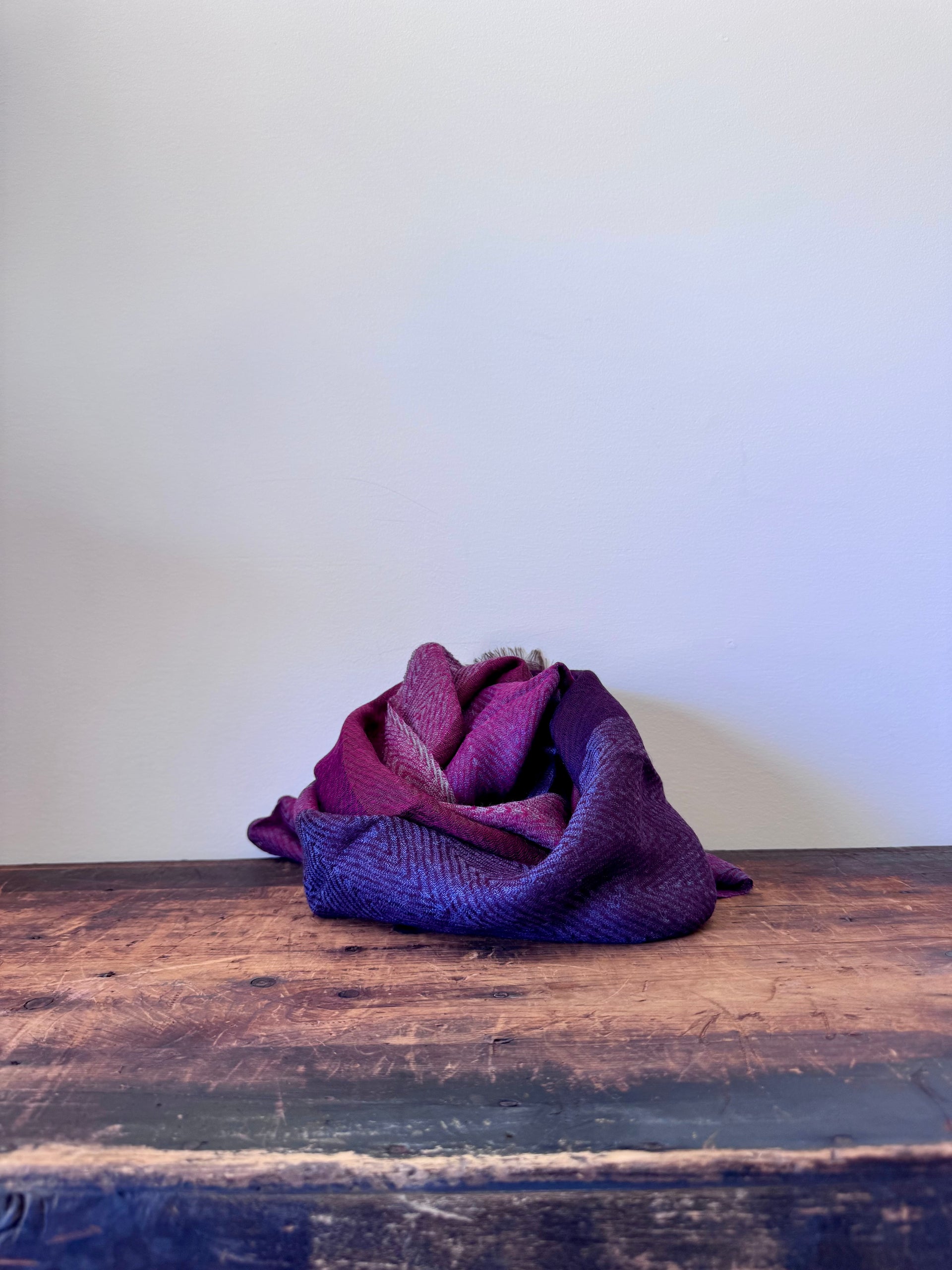 Purple fabric folded into a rose shape on a wooden surface with a white background