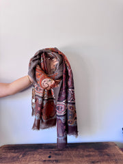 Patterned scarf draped over a wooden surface with a plain background