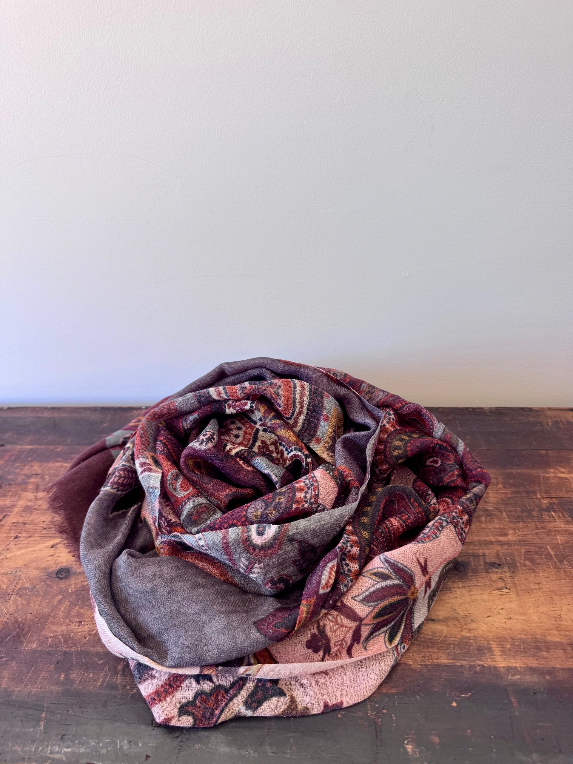 Patterned scarf on a wooden surface with a white background
