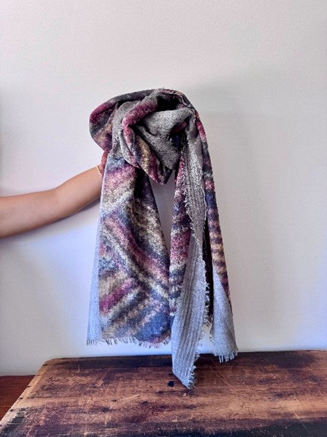 Textured blanket with a pattern held by a person on a wooden surface against a white background