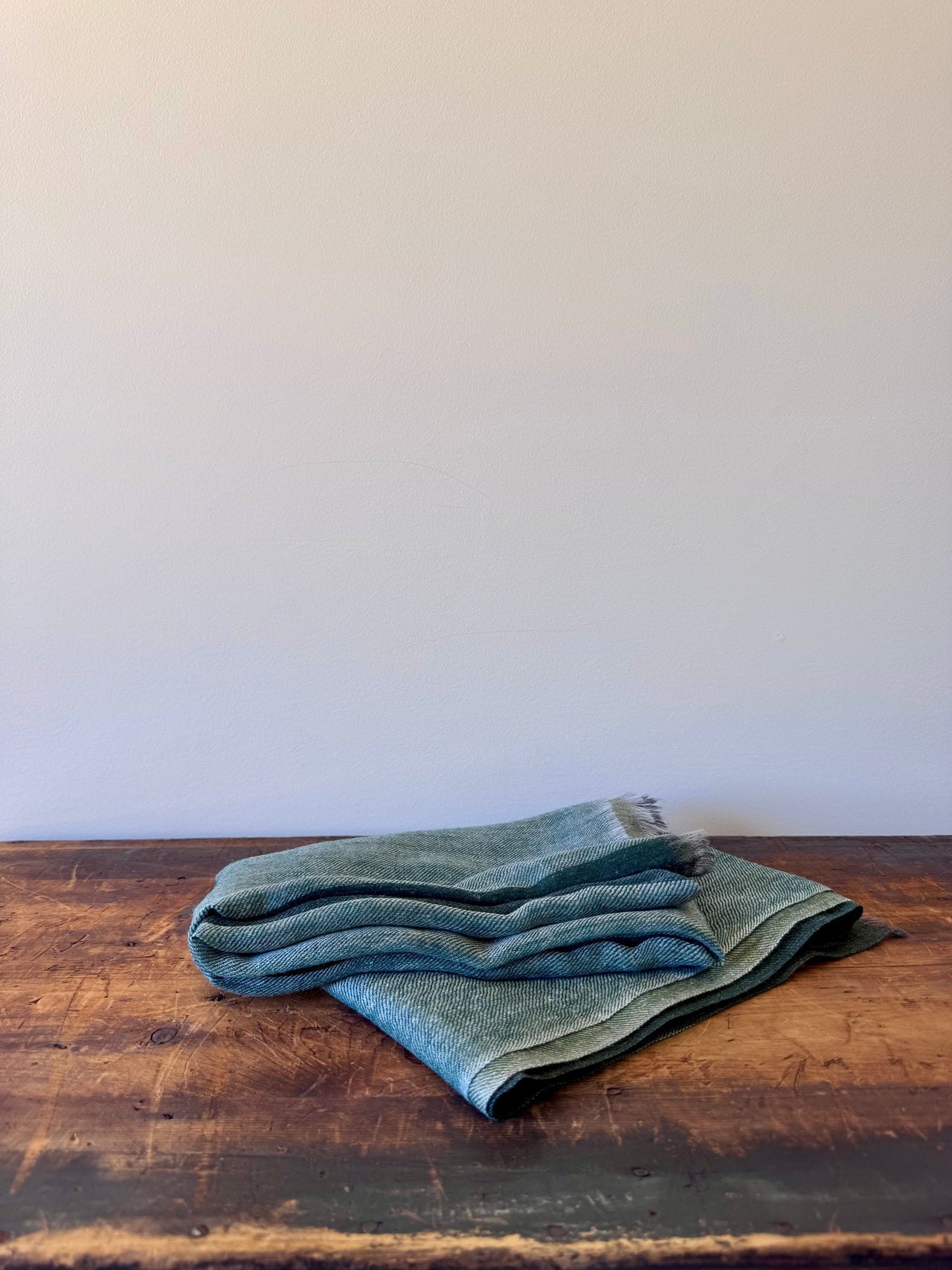 Folded green fabric on a wooden surface with a white background