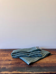 Folded green fabric on a wooden surface with a white background