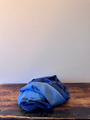 Folded blue fabric on a wooden surface with a white background