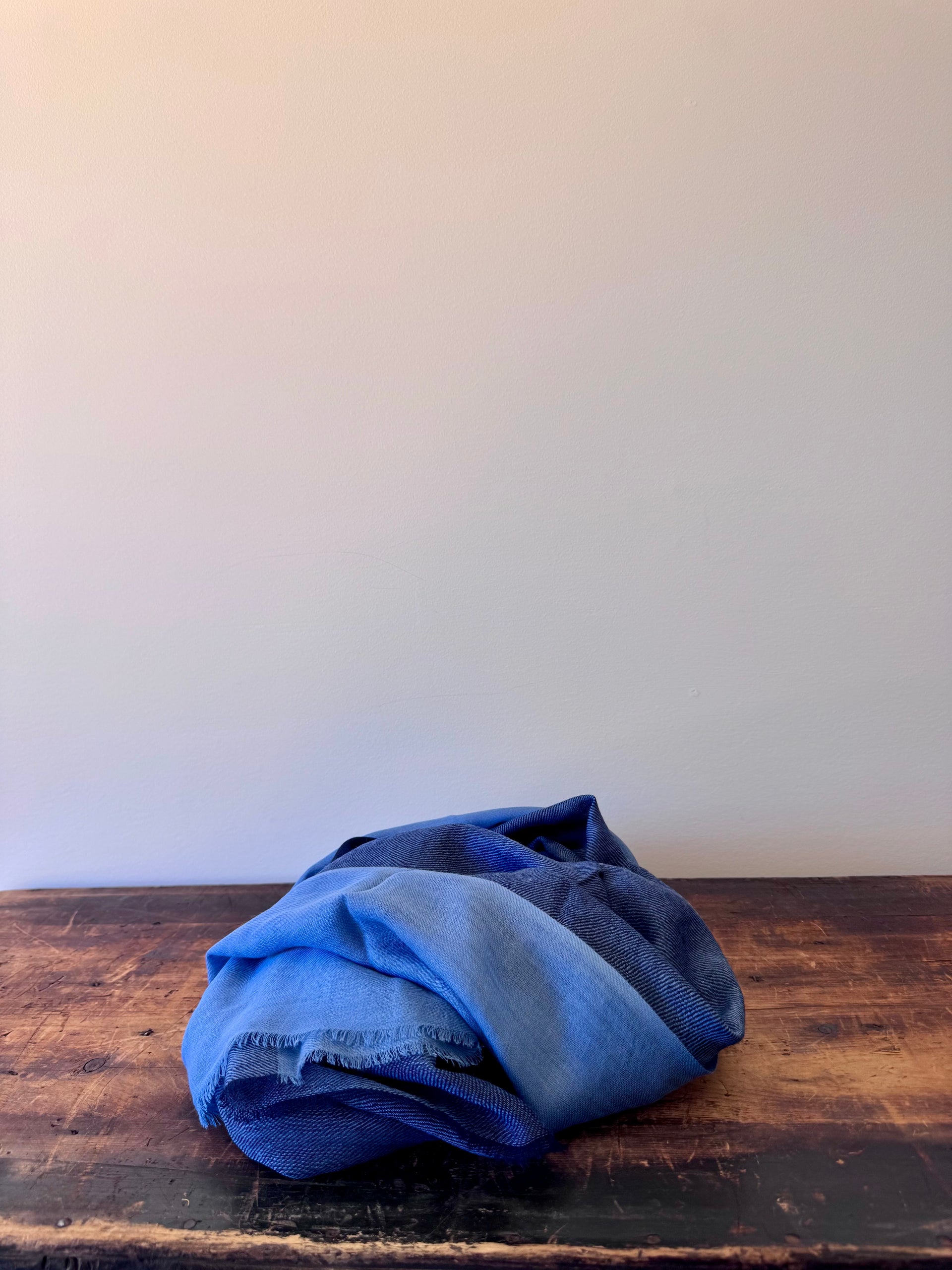 Folded blue fabric on a wooden surface with a white background
