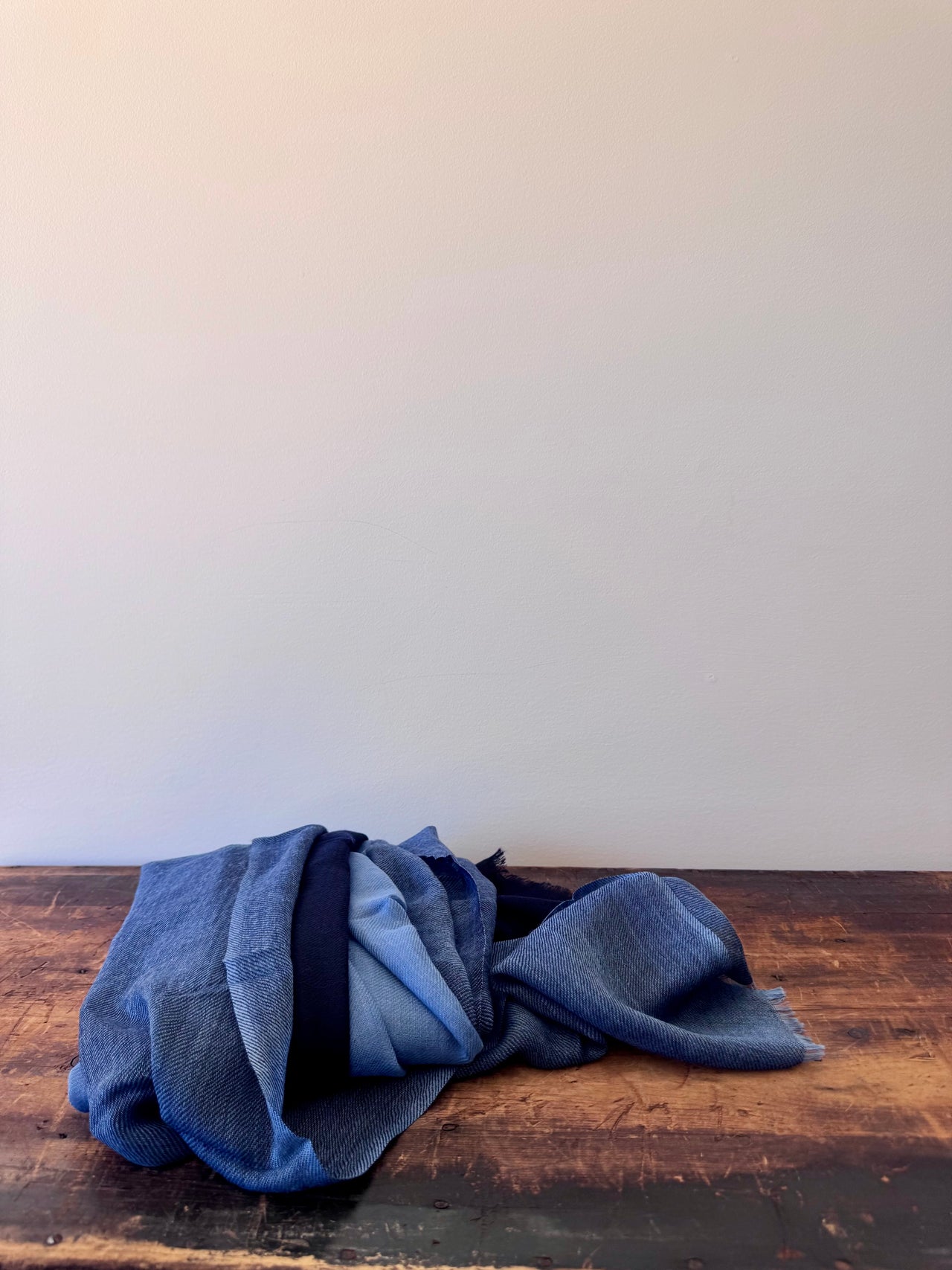 Folded blue fabric on a wooden surface with a white background