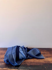 Folded blue fabric on a wooden surface with a white background