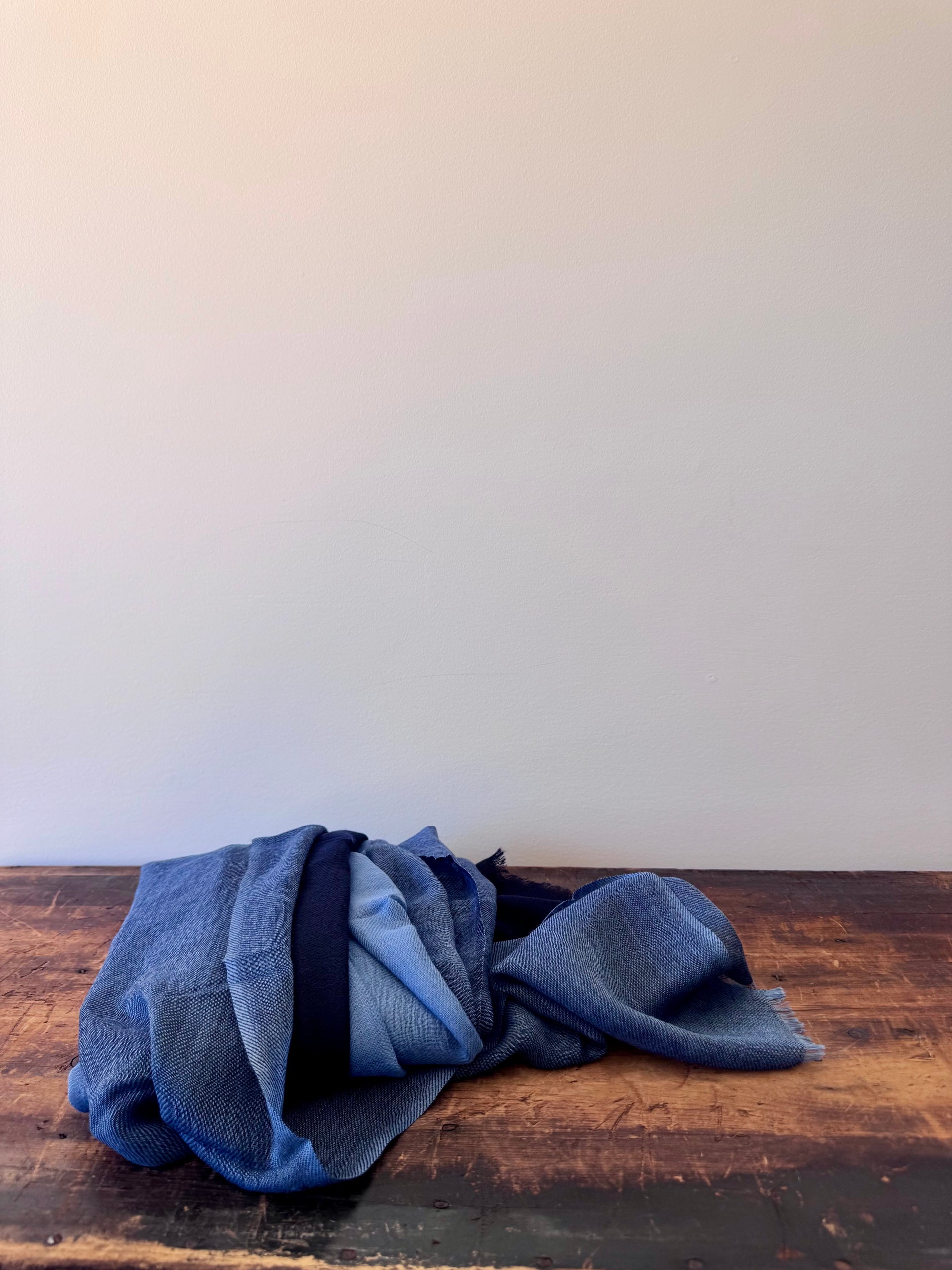 Folded blue fabric on a wooden surface with a white background