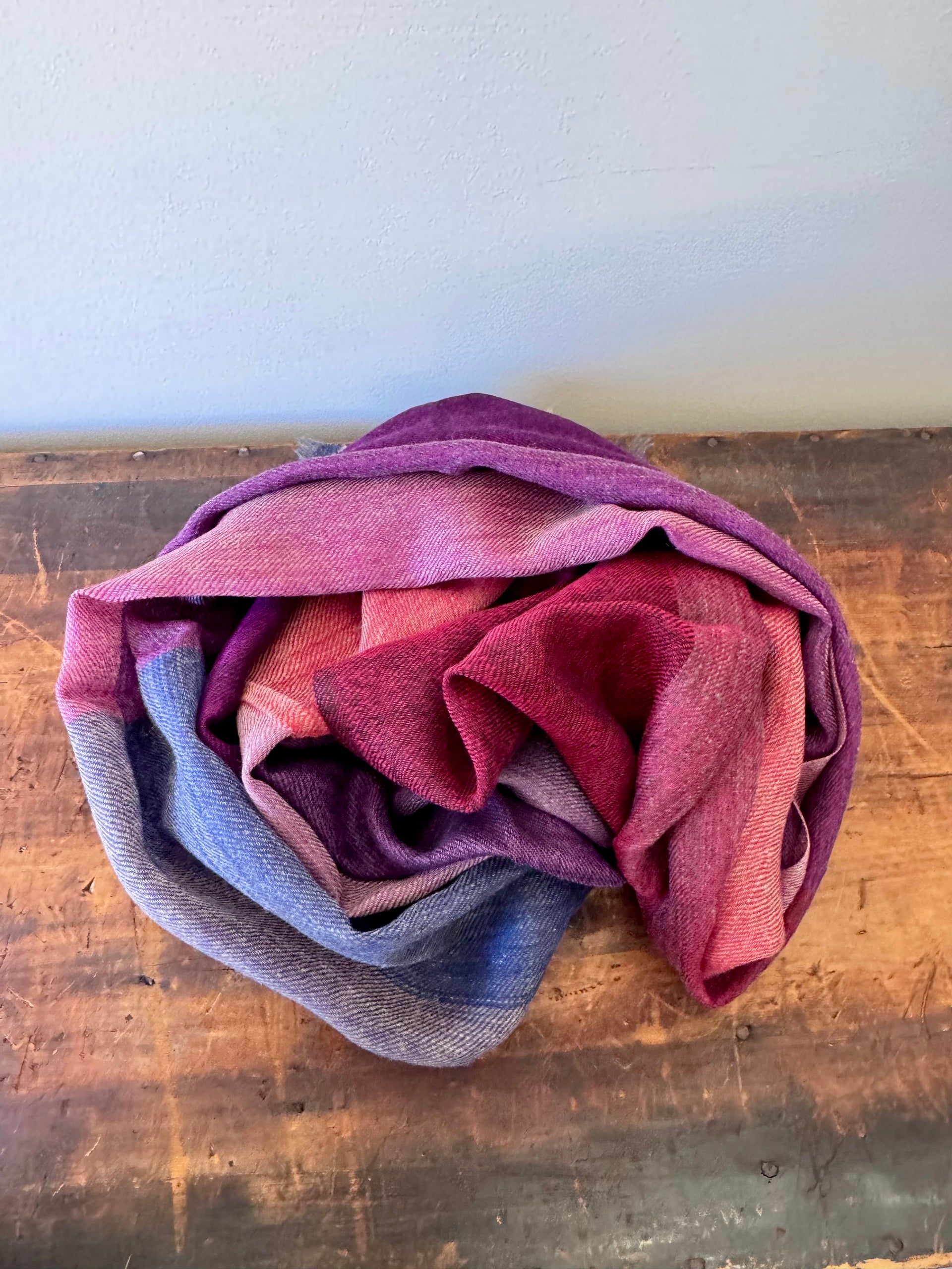 Folded fabric with purple, pink, and blue gradient on a wooden surface