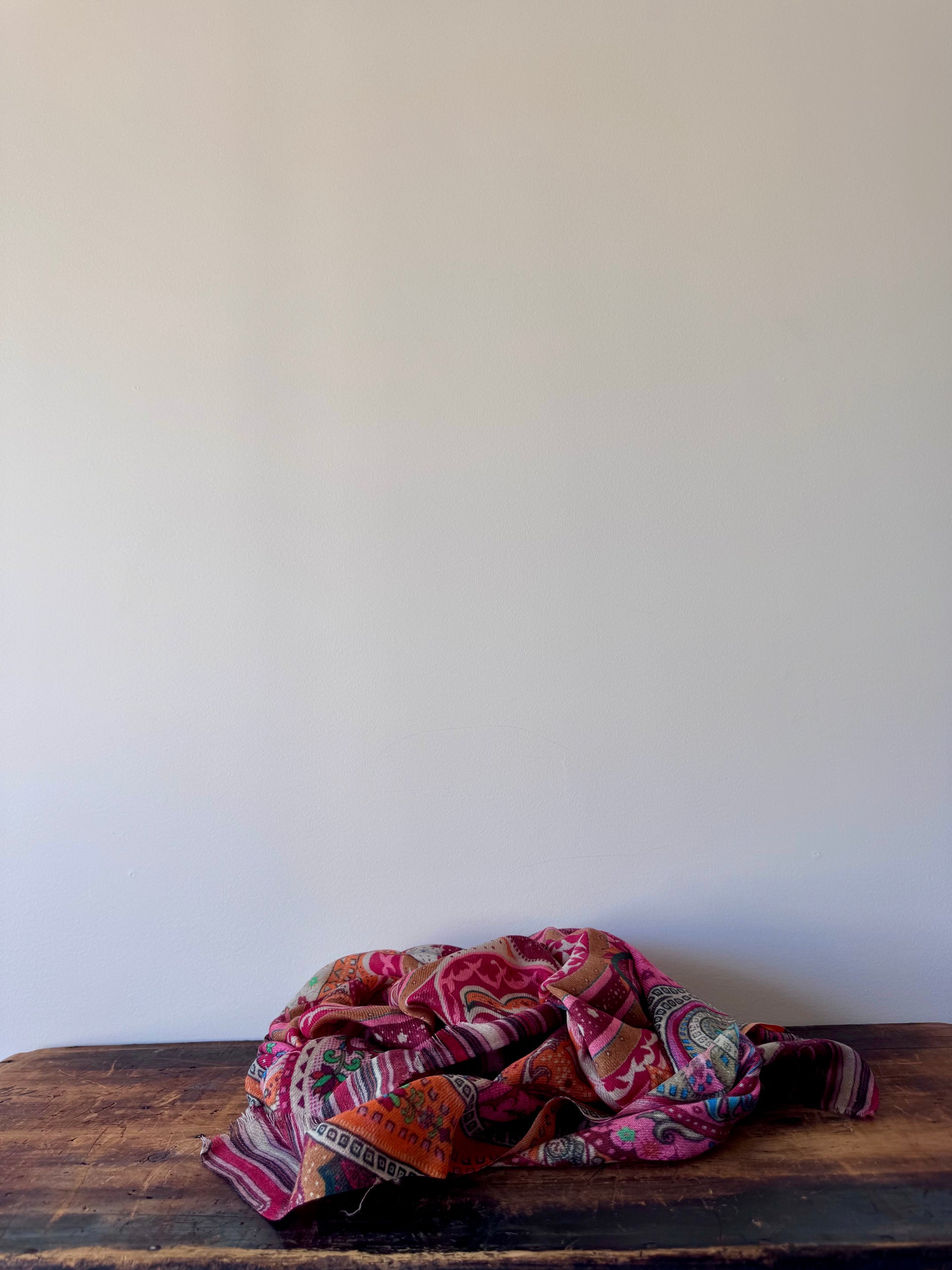 Colorful patterned fabric on a wooden surface against a white wall