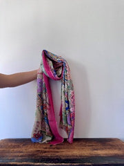 Colorful patterned scarf draped over a wooden surface with a white background