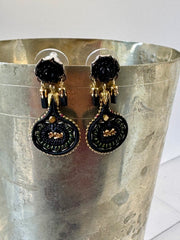 Black and gold earrings on a metallic stand against a white background