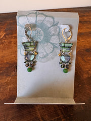 Pair of earrings with green stones in a box on a wooden surface