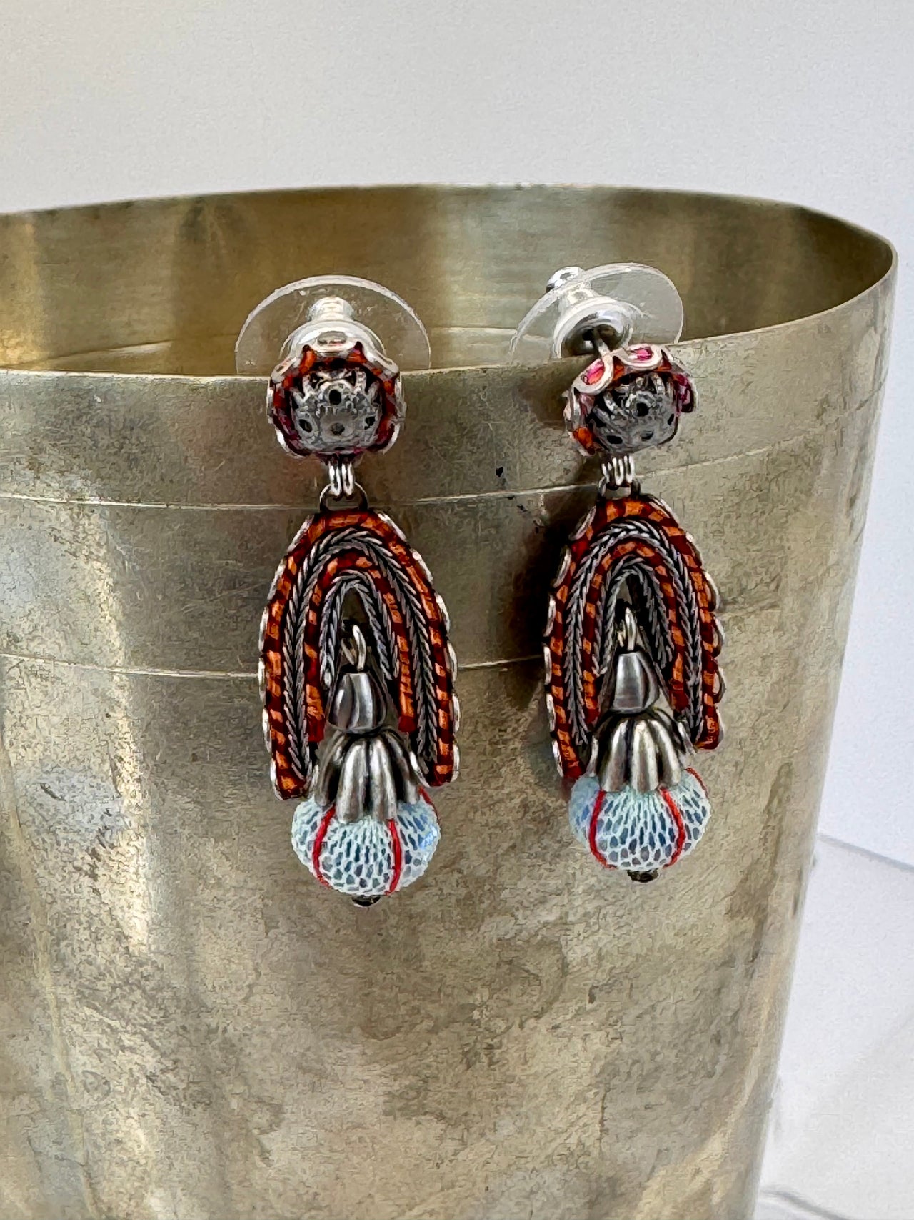 Pair of colorful earrings on a metallic surface