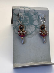 Pair of earrings with gemstones on a gray card with floral design