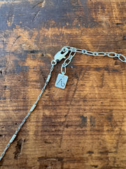 Silver chain with a tag on a wooden surface