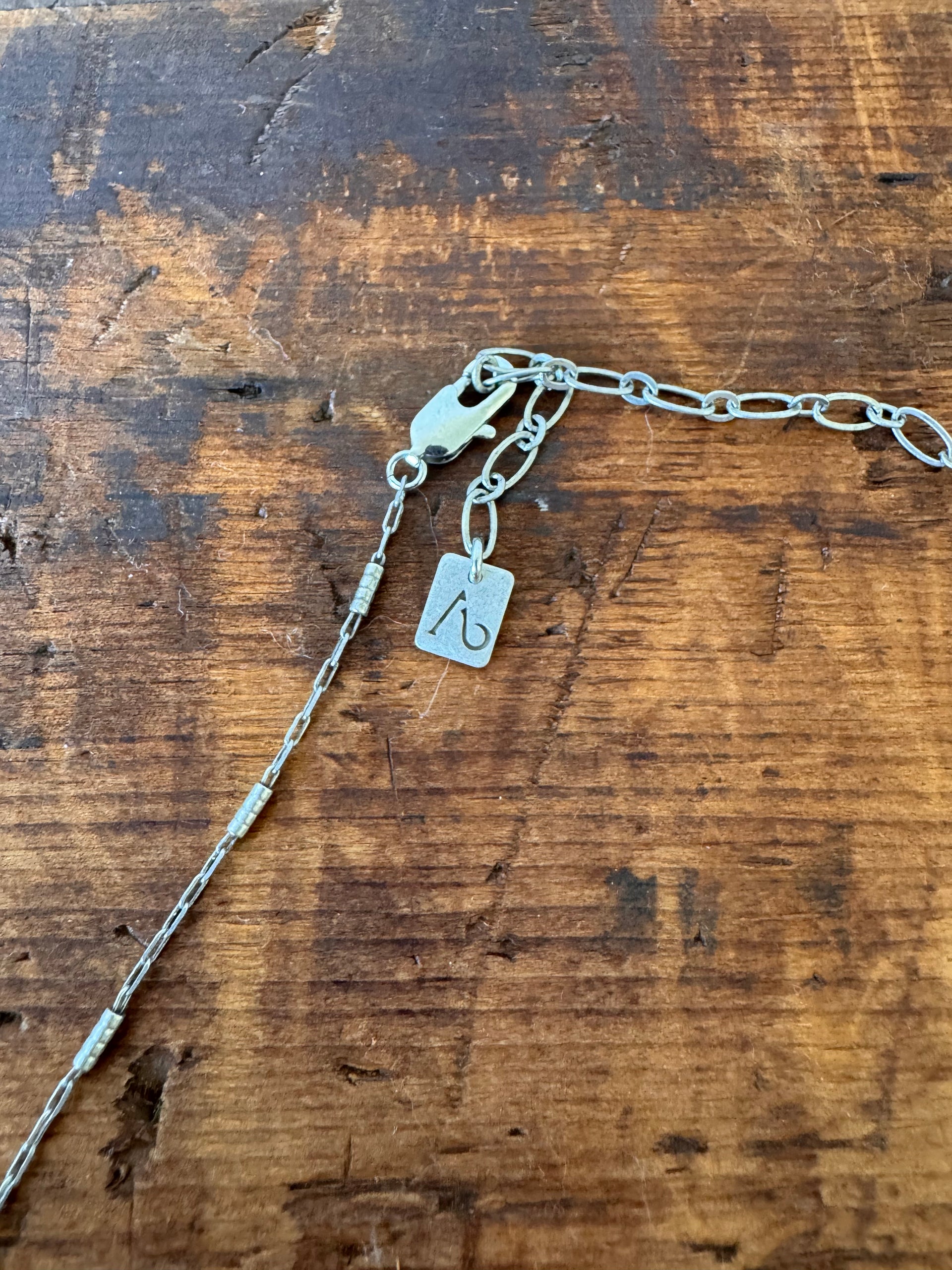 Silver chain with a tag on a wooden surface