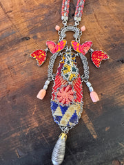 Decorative belt with colorful patterns and tassels on a wooden surface