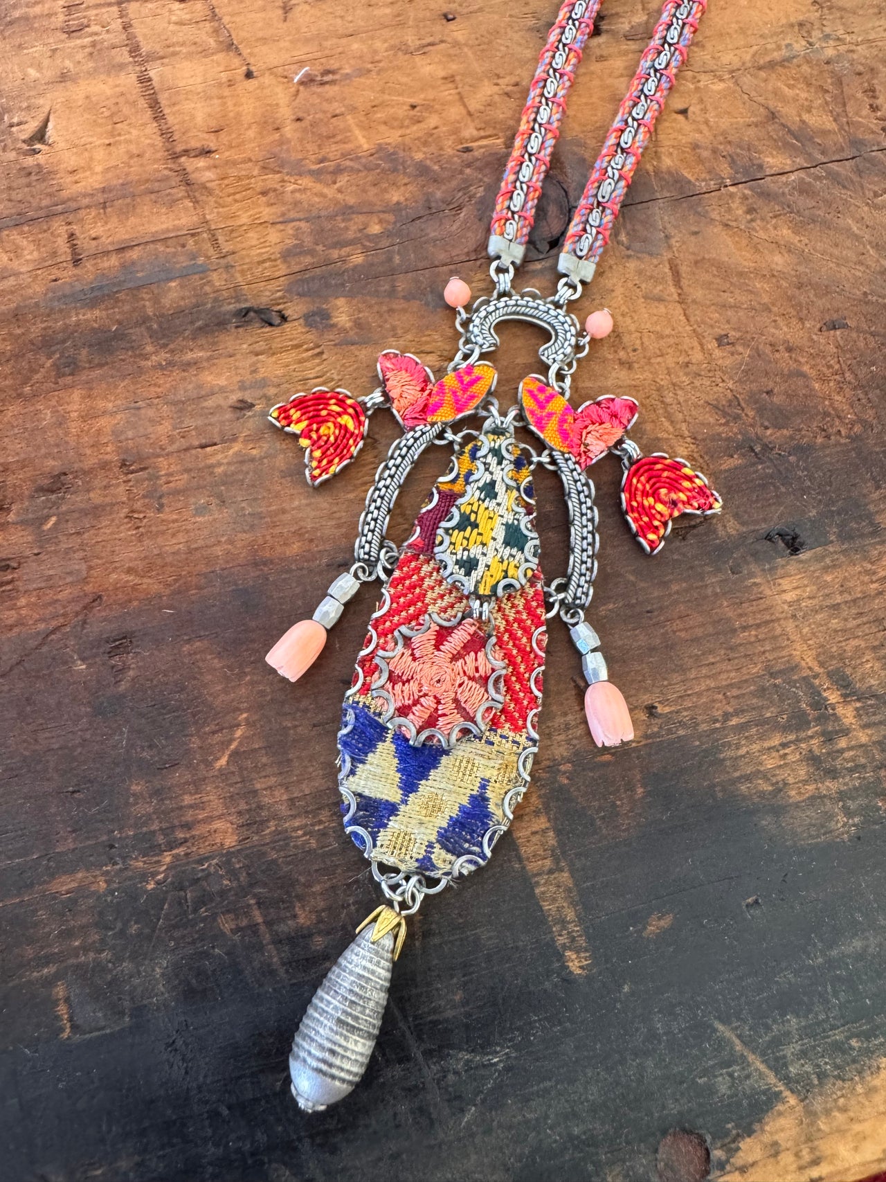 Decorative necklace with colorful beads and butterfly charms on a wooden surface