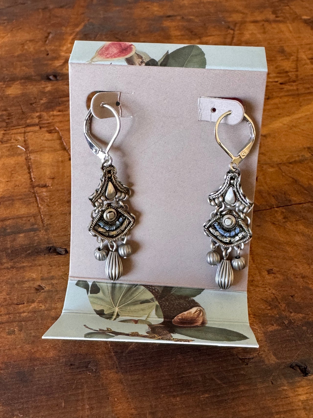 Silver bracelet with charms on a floral-patterned card on a wooden surface