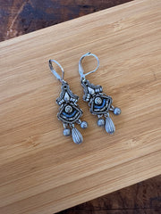 Ornate silver earrings on a wooden surface