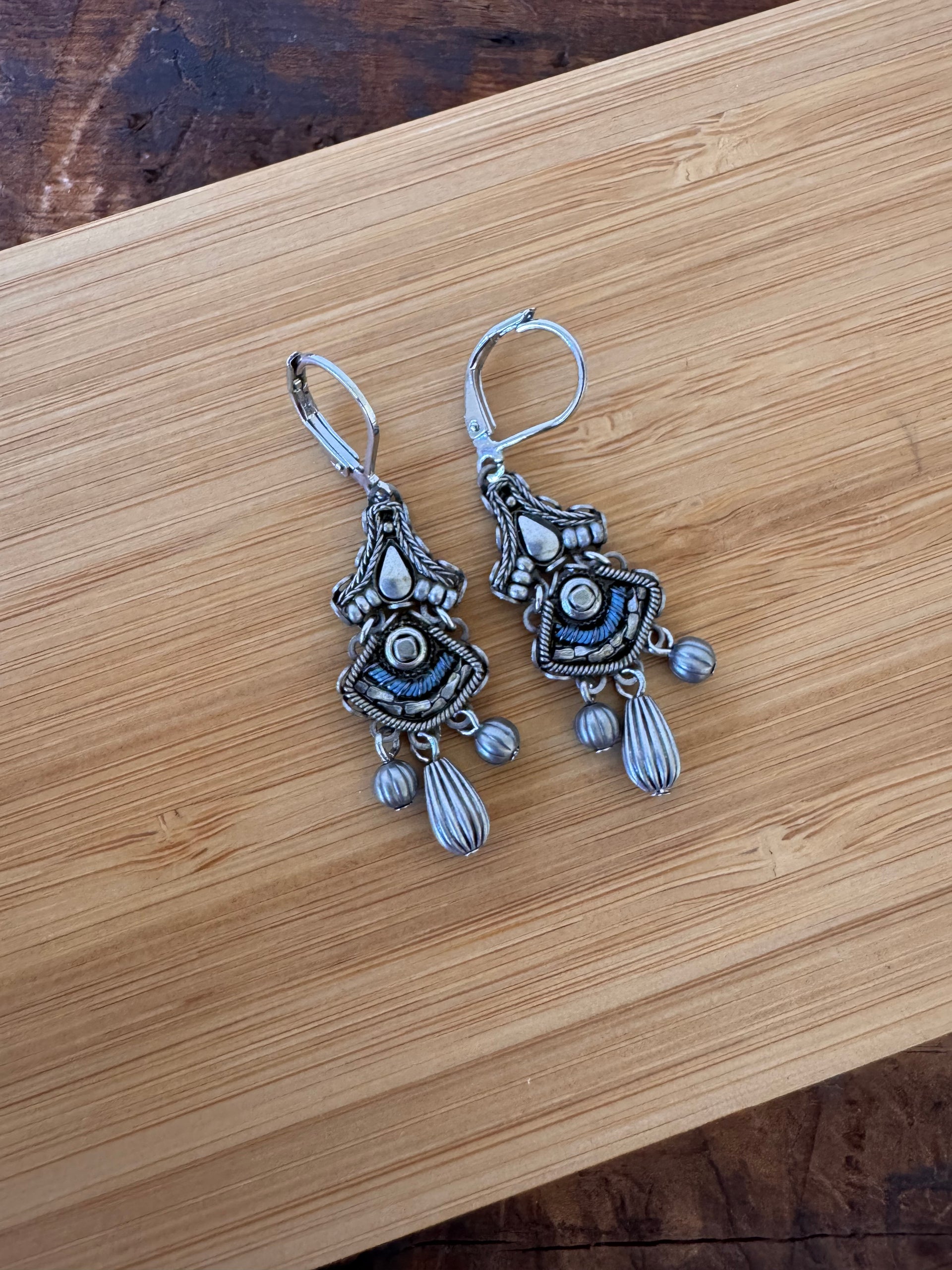 Ornate silver earrings on a wooden surface