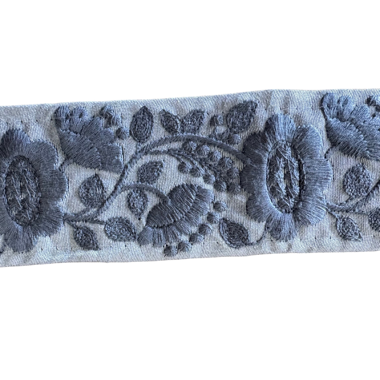 Embroidered floral pattern on a blue fabric strip