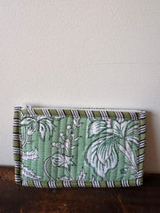 Green fabric wallet with floral pattern on a wooden surface
