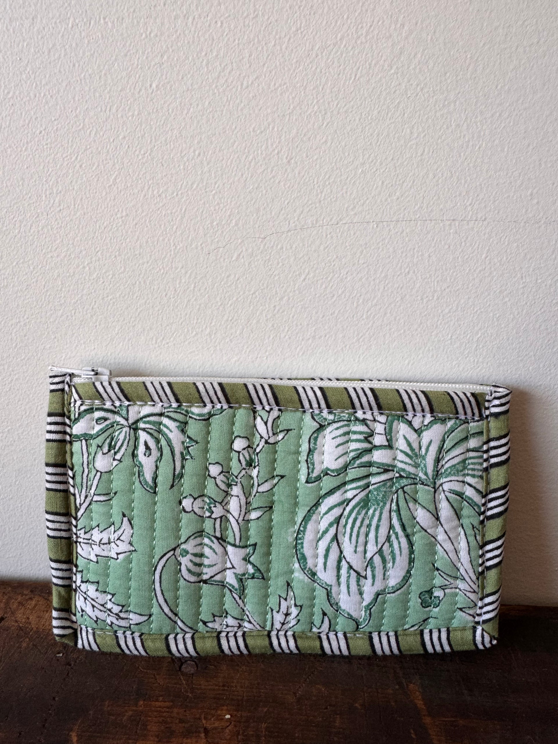 Green fabric wallet with floral pattern on a wooden surface