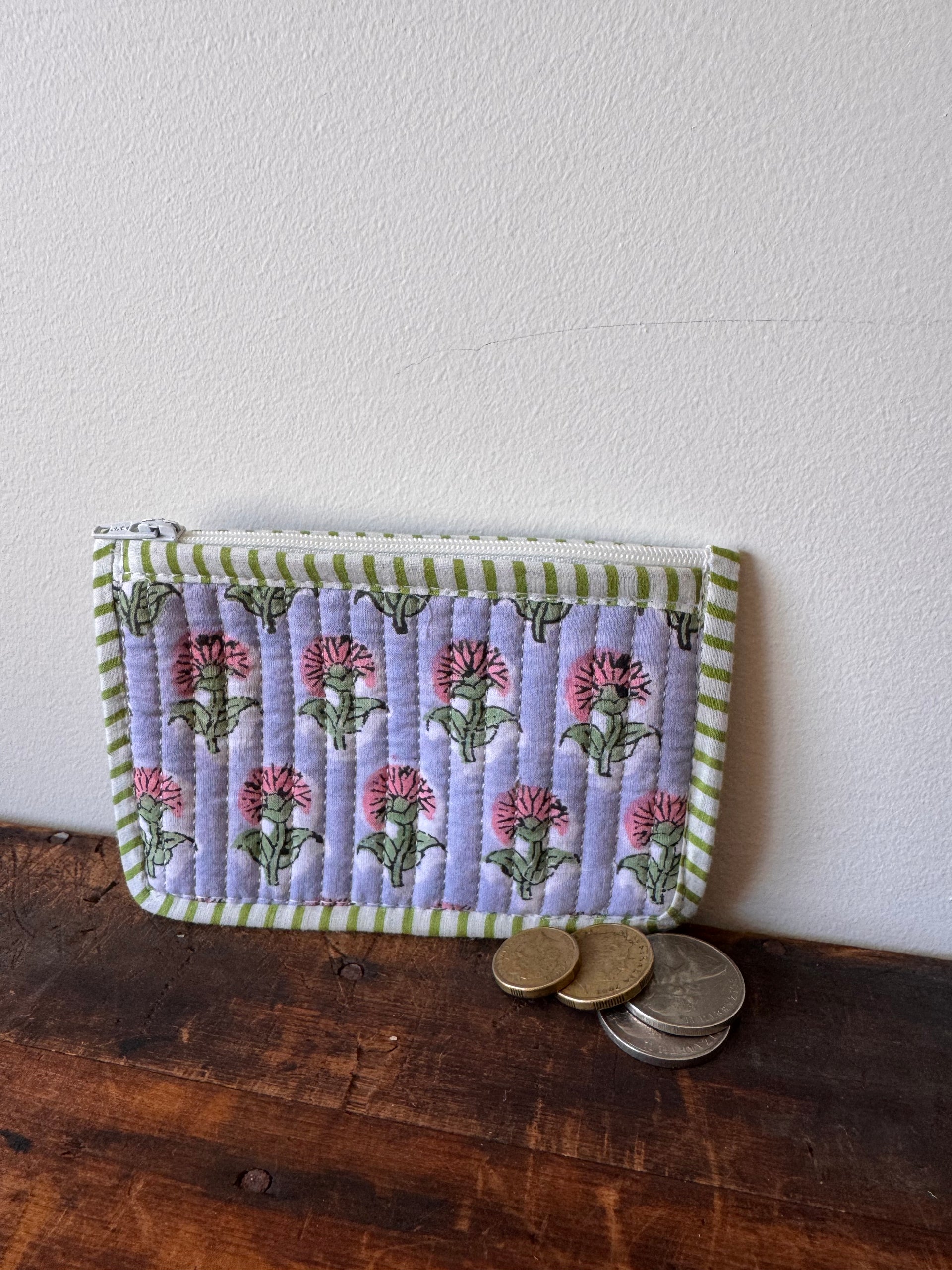 Floral-patterned fabric pouch on a wooden surface with coins.
