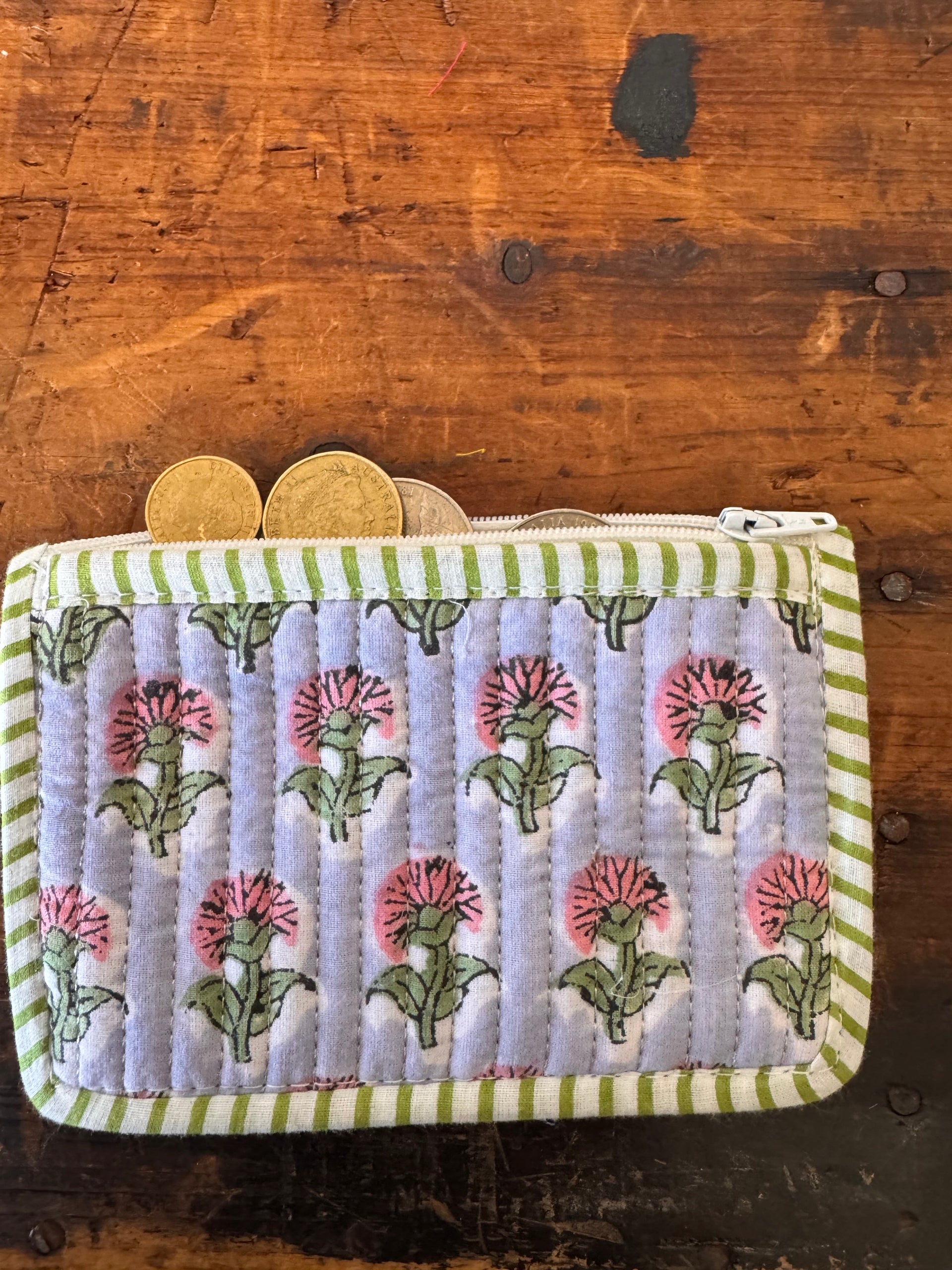 Floral patterned pouch with green stripes on a wooden surface