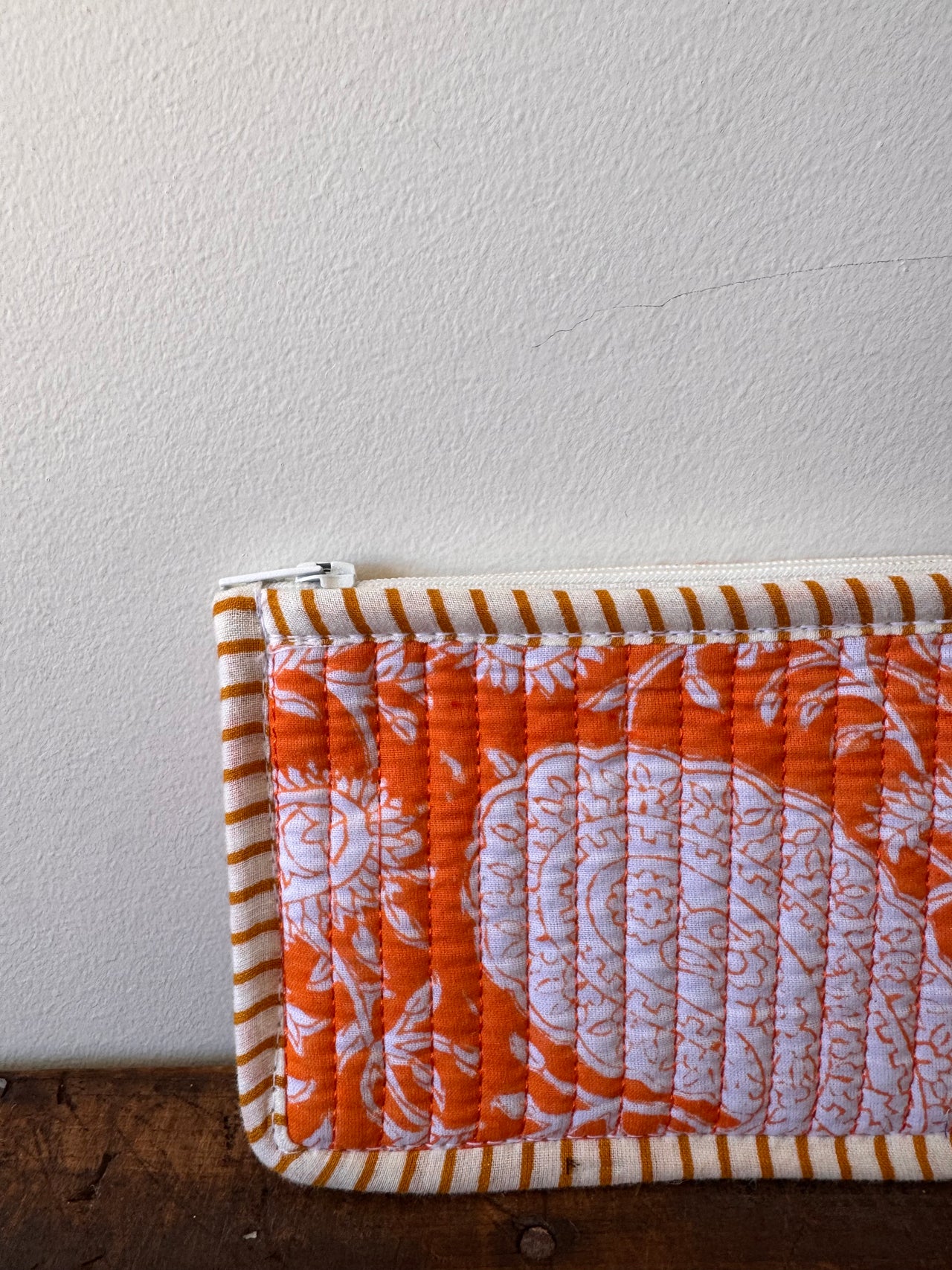 Quilted fabric with orange and white pattern on a plain background
