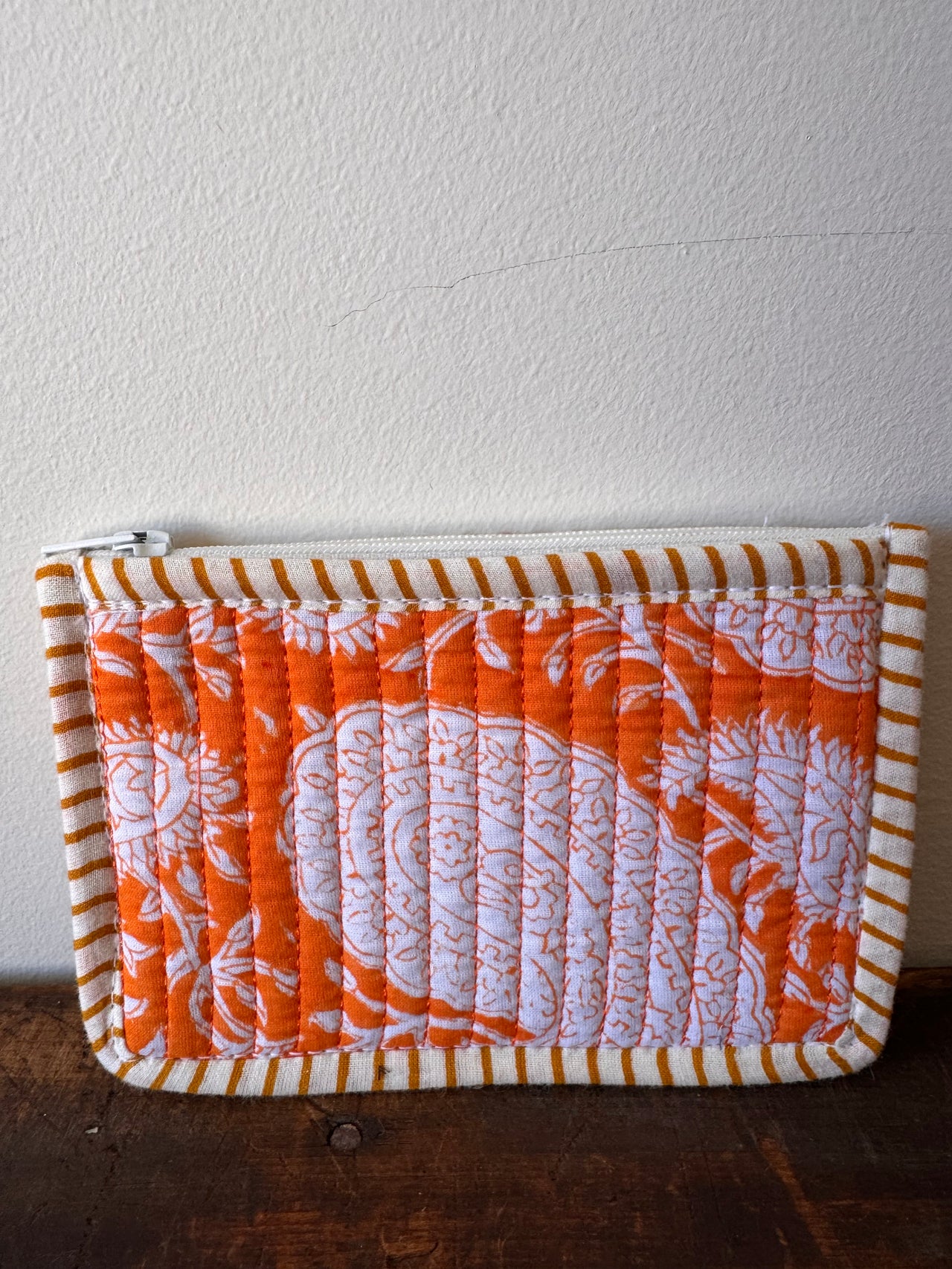 Quilted orange and white patterned fabric on a wooden surface