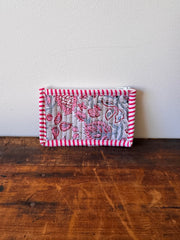 Small quilted fabric square with floral and striped patterns on a wooden surface.