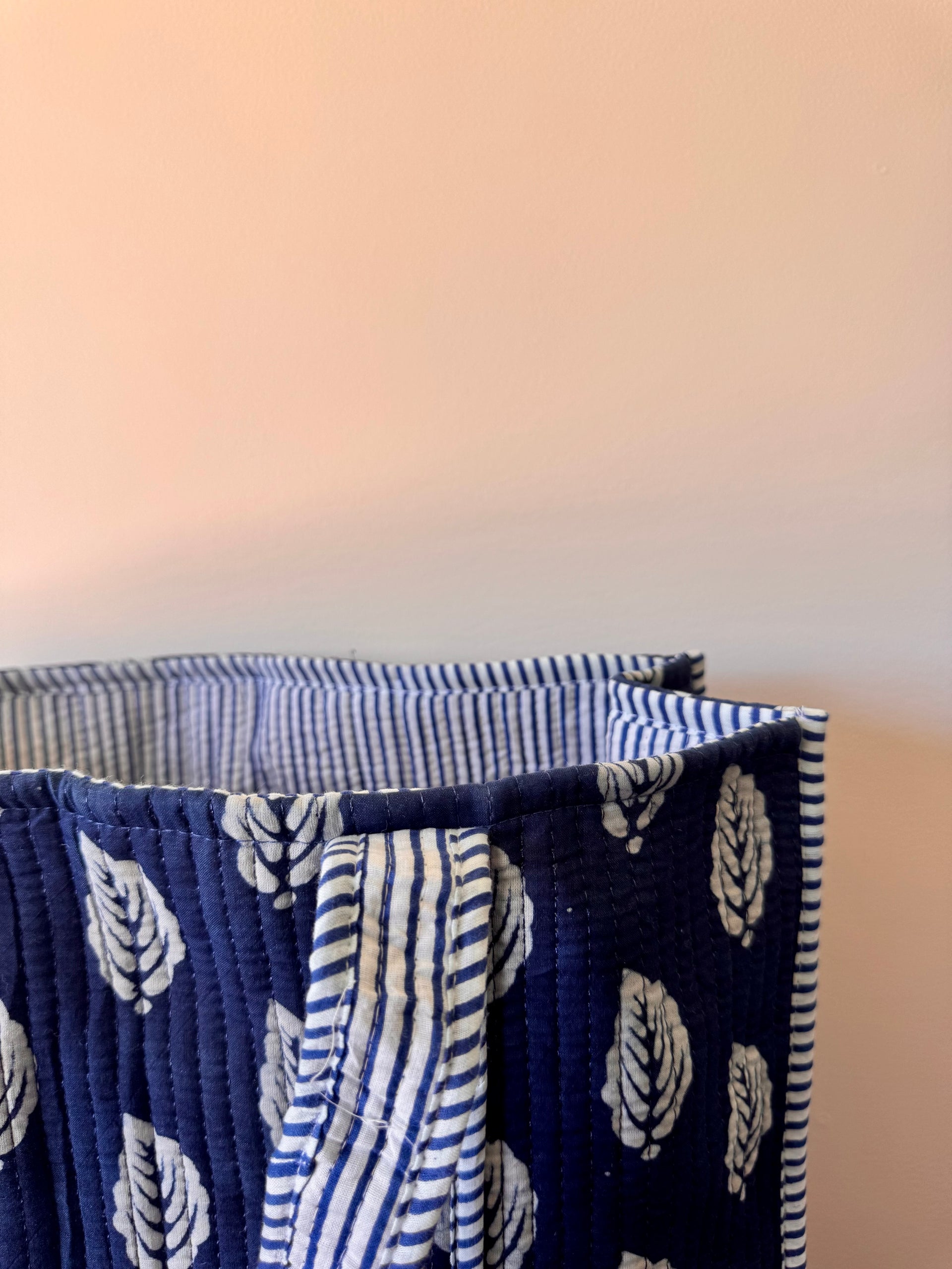 Stack of folded fabric items with blue and white patterns on a neutral background