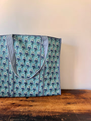 Tote bag with floral pattern held by a person against a neutral background