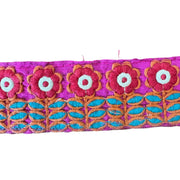 Embroidered fabric strip with floral design on a pink background