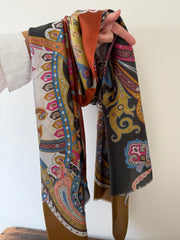 Colorful patterned scarf held by a person against a white background