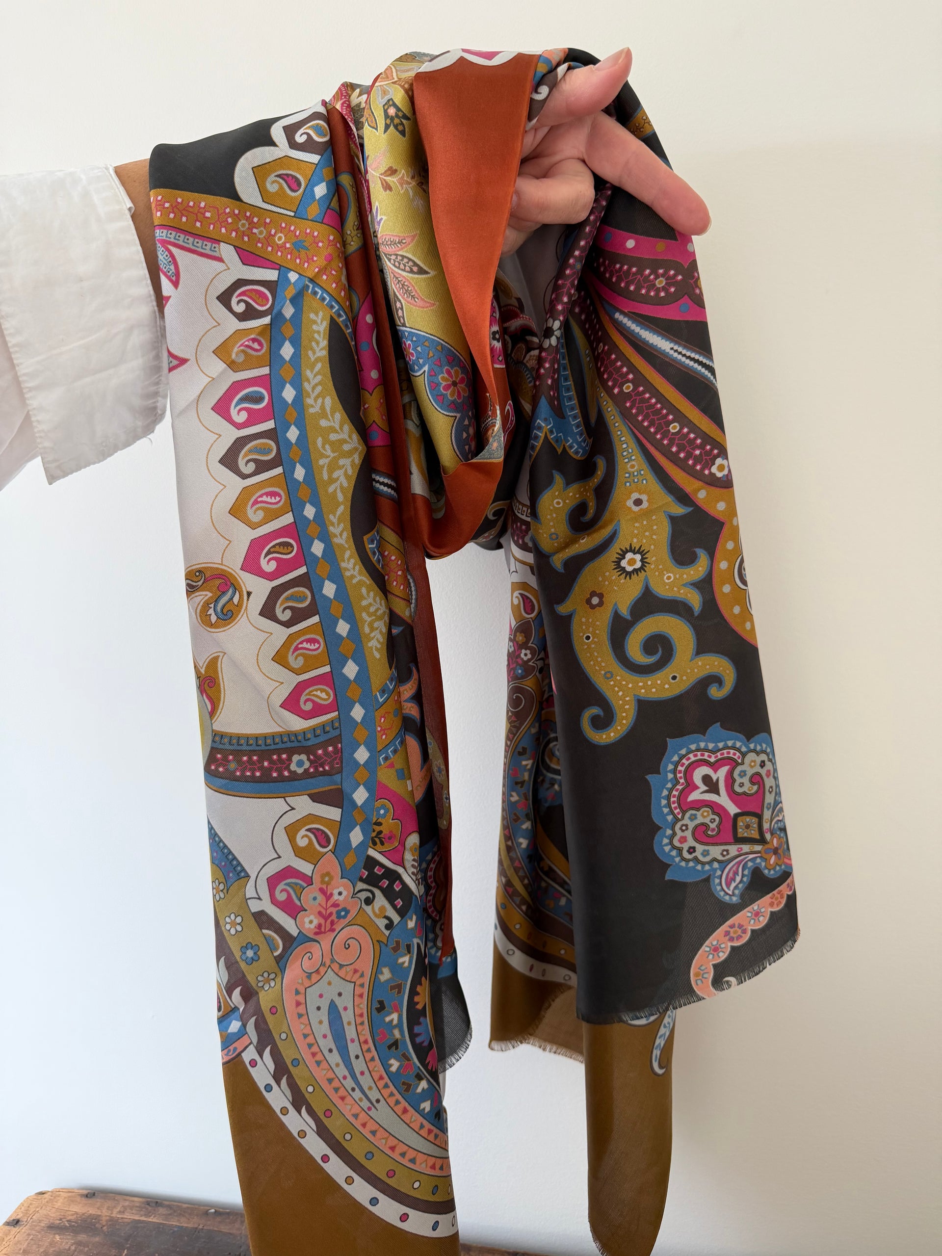 Colorful patterned scarf held by a person against a white background