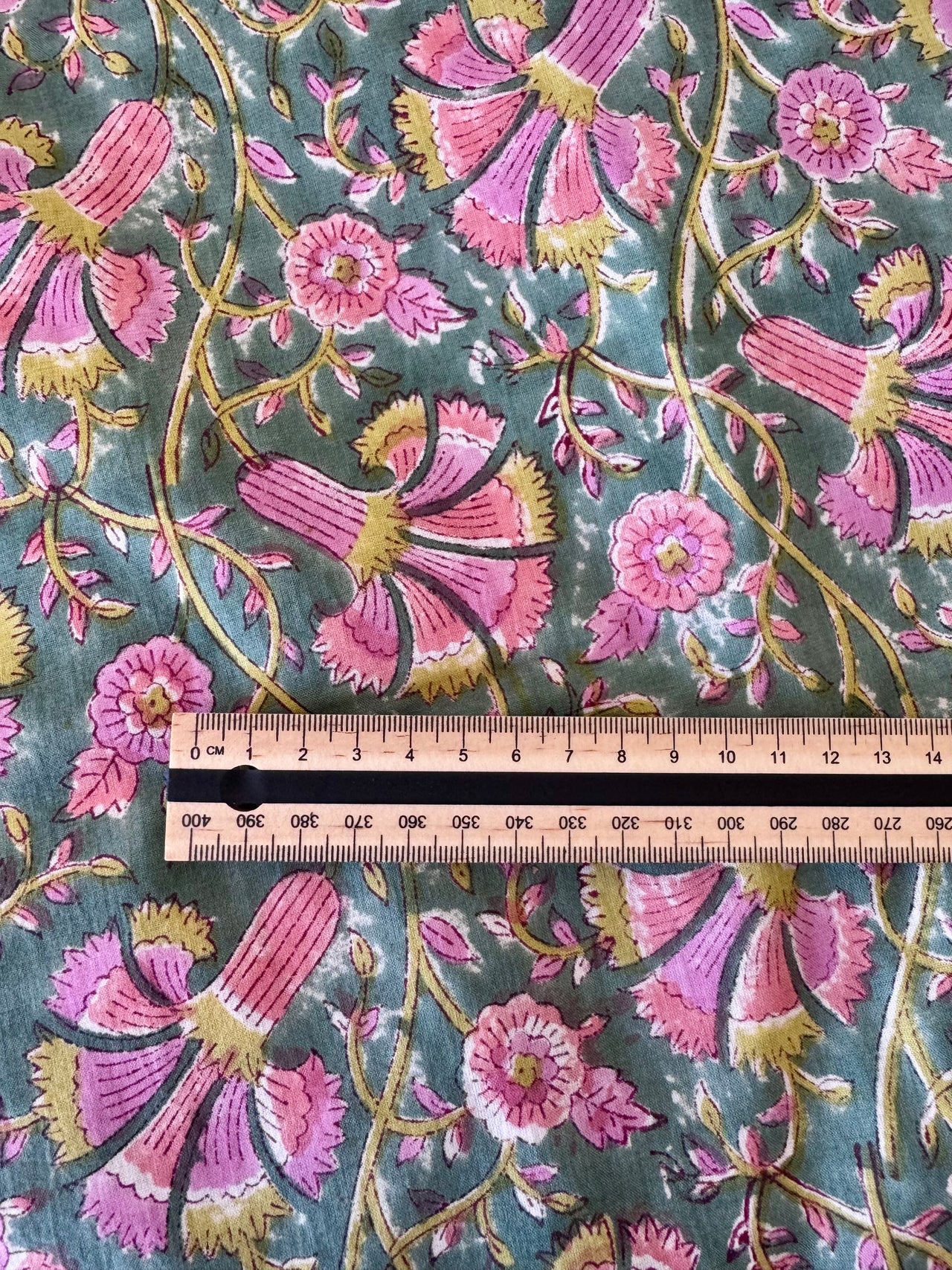 Floral fabric pattern with a ruler for scale on a green background