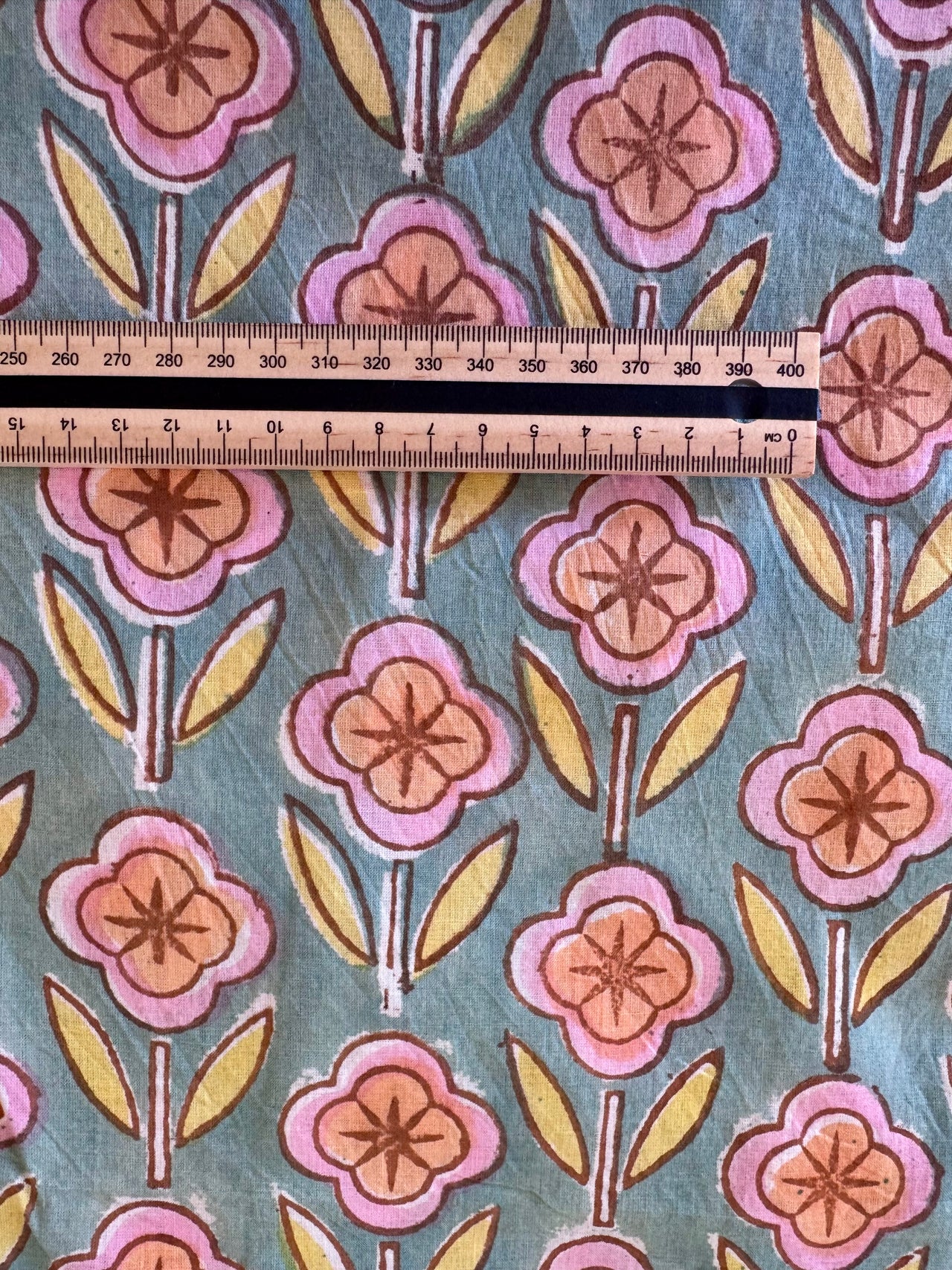 Floral patterned fabric with a ruler for scale on a blue background