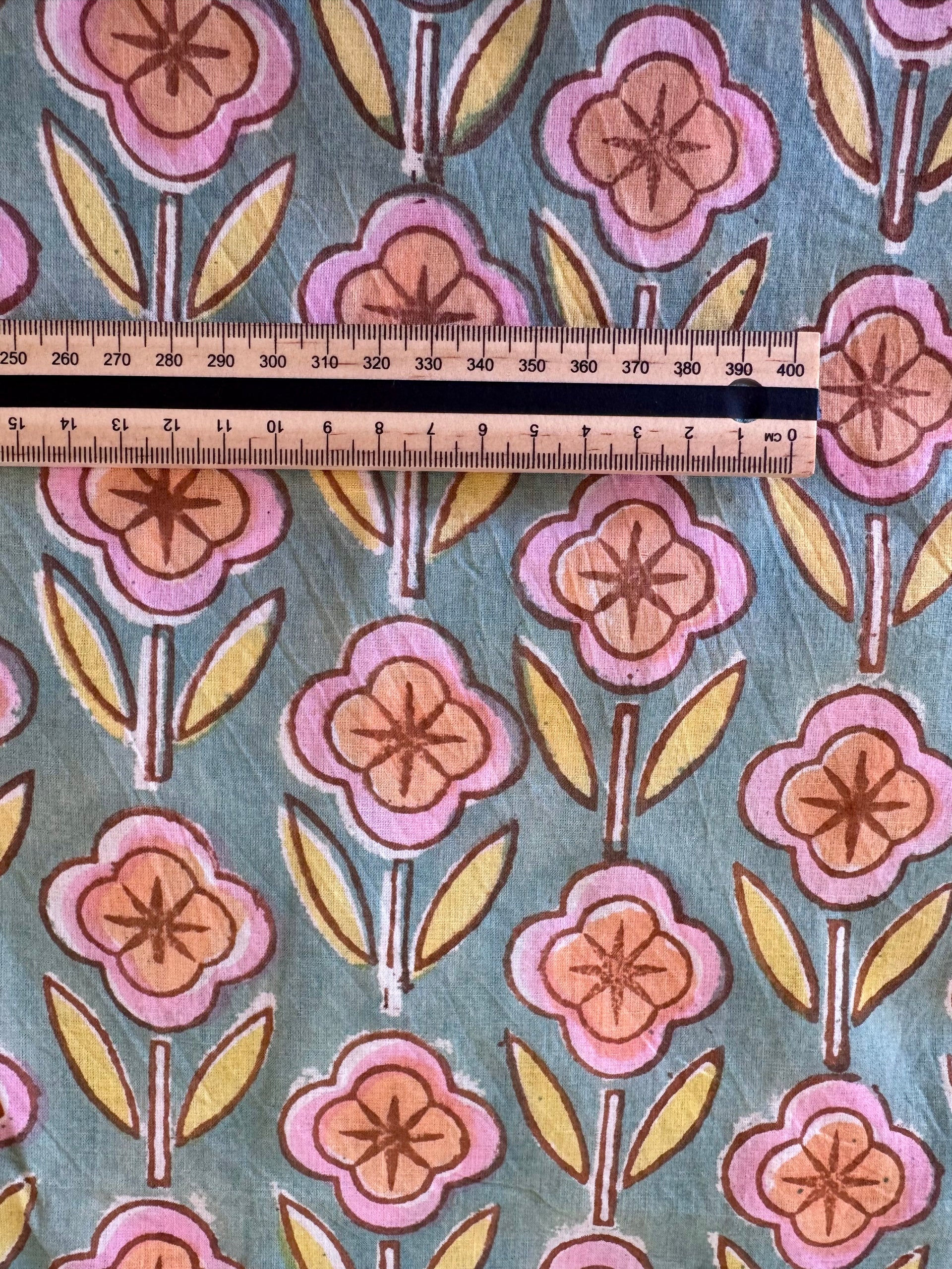 Floral patterned fabric with a ruler for scale on a blue background