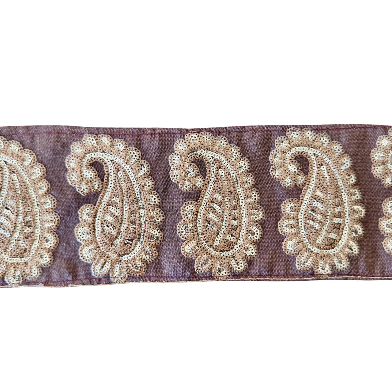 Decorative ribbon with gold paisley patterns on a purple background