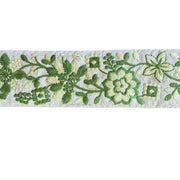 Embroidered floral pattern with green and white flowers on a textured background